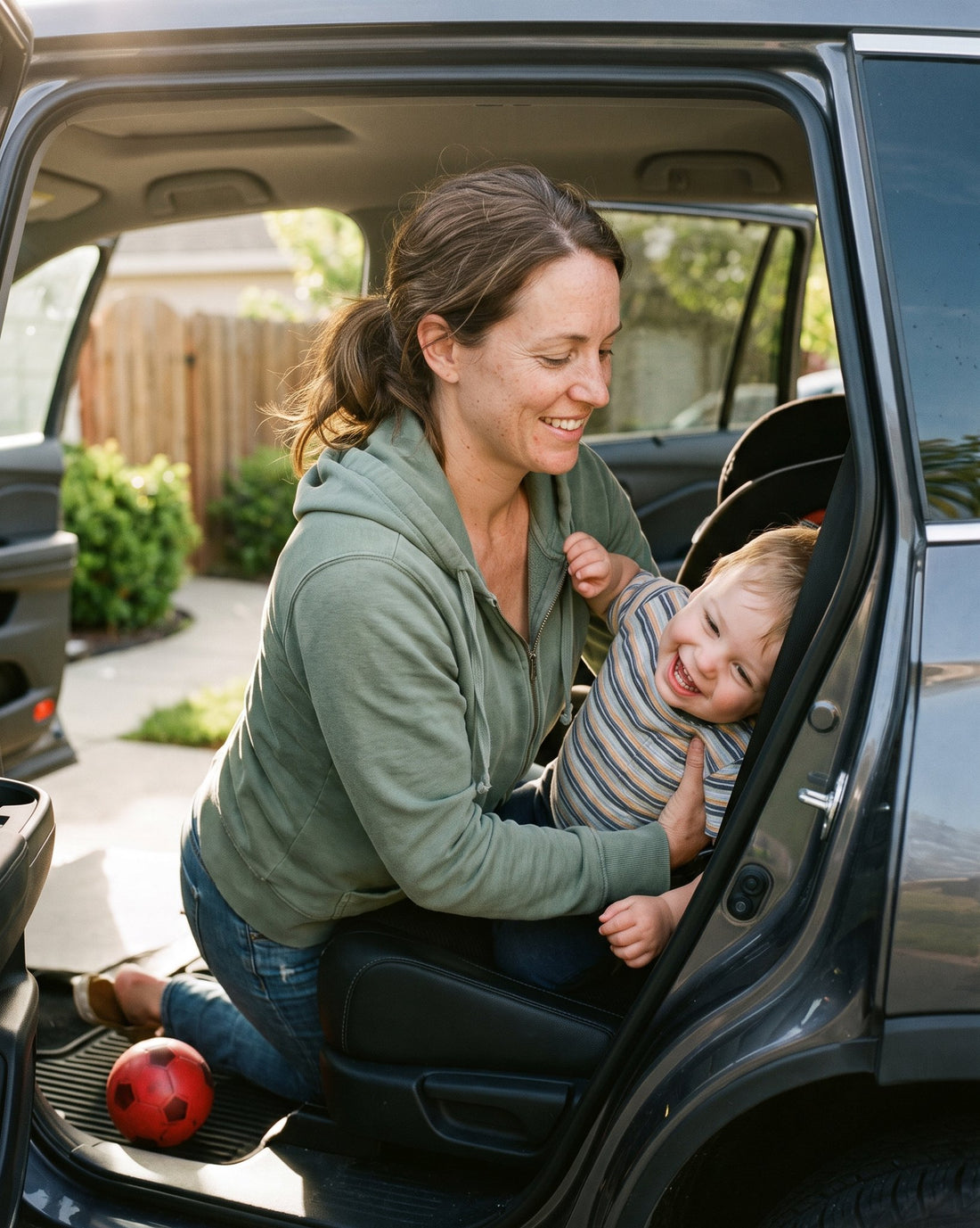 Mom easily lifting her laughing toddler into a car seat